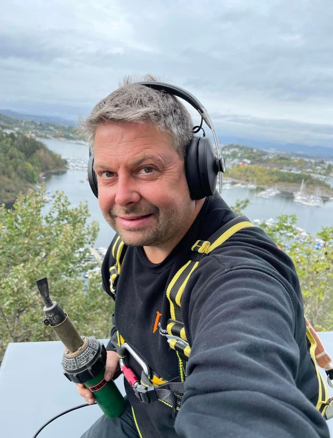 Jan Thomas Ekstrøm med hørselvern og sele, med utsikt over vann